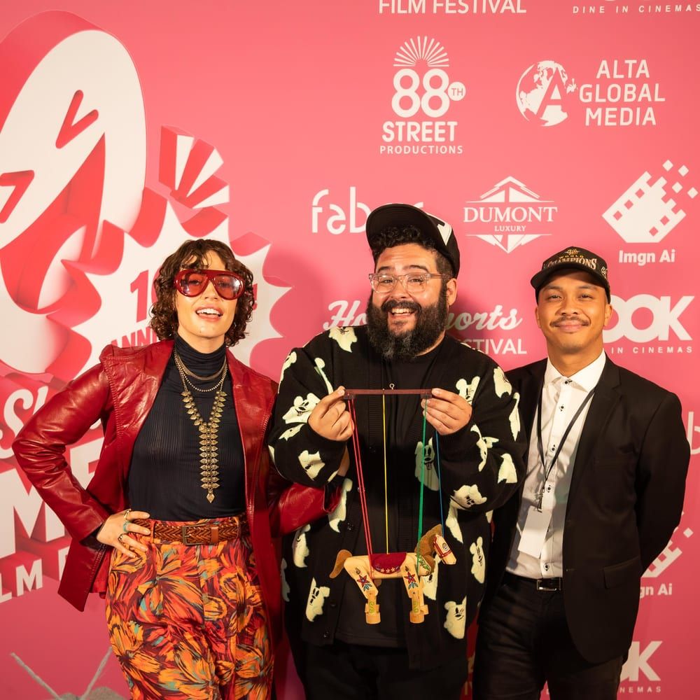 Whitney Moore and Steve Zaragoza, holding the wooden horse puppet, with a teammate on the HollyShorts red carpet