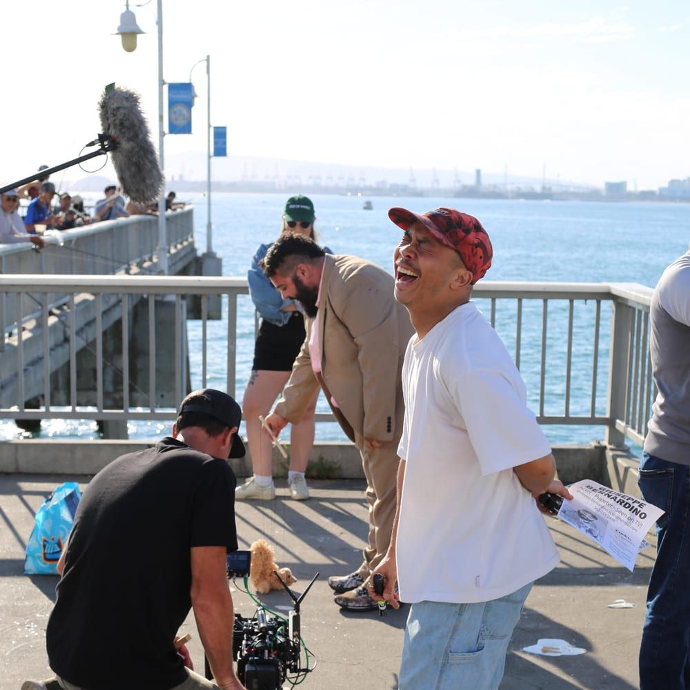 Cast and crew filming a scene on a seaside pier
